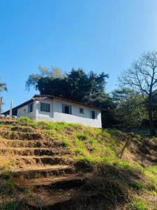 波苏阿莱格里Chácara Vale dos Eucaliptos的山顶上带楼梯的白色房子