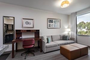 卡尔斯巴德Staybridge Suites Carlsbad/San Diego, an IHG Hotel的客厅配有书桌和沙发。