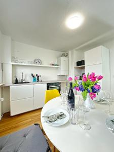 卡塞尔Cleo Apartments的白色的厨房,配有带鲜花的桌子
