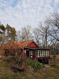 尼雪平Ekbacken - naturskön stuga med närhet till havet的前面有长凳的红色小房子