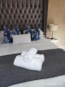 RandburgOnyx Luxury cottage的一张带毛巾的床,带大床头板