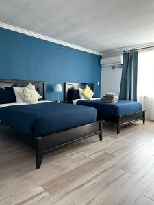 洛杉矶Hometel Suites的一间卧室设有两张床和蓝色的墙壁