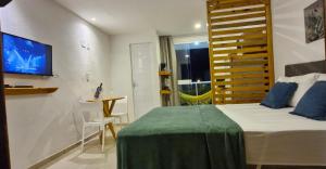 帕里普埃拉MSFlats Paripueira Aconchegante, Moderno Praia Mansa的一间卧室配有一张床、一张桌子和一台电视。