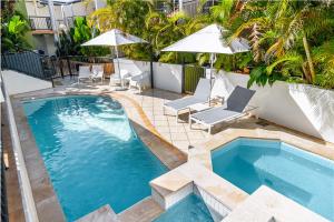 拜伦湾Eco Beach Resort的一个带两把椅子和遮阳伞的游泳池