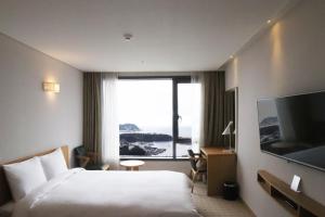 西归浦市Jeju Hotel the M的酒店客房设有一张床和一个大窗户