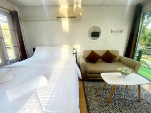 北冲Sleep Home Khaoyai的一间卧室配有一张床、一张沙发和一张桌子