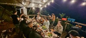 大叻Nhà Bên Suối - Homestay & Camping的一群坐在餐桌上吃食物的人