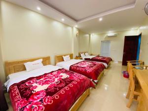 Bản PiênKim Thoa Hotel Trung Khanh的两张位于酒店客房的床铺,配有红色床单