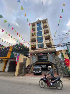 Bản PiênKim Thoa Hotel Trung Khanh的骑摩托车的人在一座悬挂旗帜的建筑前