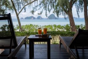 塔可克海滩Tup Kaek Sunset Beach Resort-SHA Plus的两只橙色花瓶坐在甲板上的桌子上