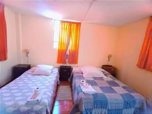 阿雷基帕Fernanda apartment的小房间设有两张床,配有橙色窗帘