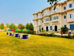乌代浦Jag Aravali Resort Udaipur- Experience Nature away from city Hustle的前面有桌子和伞的建筑