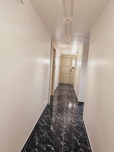 艾哈迈达巴德HOTEL R K VILLA的一条空的走廊,铺有黑色大理石地板,拥有白色的墙壁