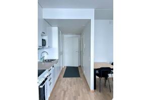 奥卢奥卢家居庭公寓的厨房配有白色橱柜和餐桌