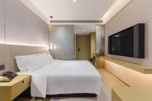 深圳漫时酒店(深圳大学科技园店)的卧室配有白色的床和平面电视。