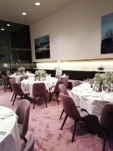 科特赖克梅塞恩酒店的一间设有白色桌椅和屏幕的用餐室