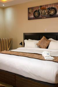 卢萨卡Milestone Hotels的一张位于酒店房间的床,墙上挂着摩托车