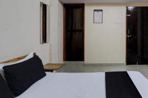 那格浦尔OYO 8195 The Hotel Lotus Inn的卧室配有一张带黑色枕头的白色床和一扇门。