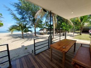 Ban Pak Nam Pak DuatLoma Beach Resort的一个带木桌的门廊,享有海滩美景
