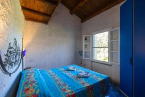 San NicolòVilla Teresa Country Lodges的一间设有蓝色床的卧室,位于一个设有窗户的房间