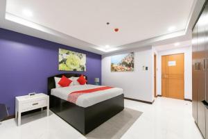 马尼拉AMORE HOTEL MANILA的一间卧室配有一张床和紫色的墙壁