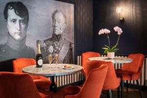 勒谢奈Mercure Versailles Paris Ouest的一间设有两张桌子的餐厅,还有一幅画画