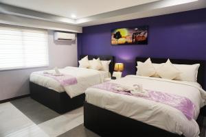马尼拉AMORE HOTEL MANILA的紫色墙壁客房的两张床