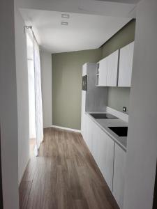 维罗纳CALLA, CALLUNA & GARDENIA APARTMENTS的厨房铺有木地板,配有白色橱柜。