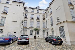 巴黎Pick A Flat's Apartments in Place des Vosges - Rue de Birague的两辆汽车停在一座大建筑前面