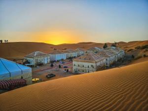 梅尔祖卡Merzouga Tents © Official的沙漠中一群建筑物,日落