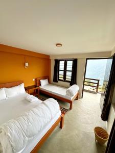 AstamHill Top Lodge Ghandruk的一间卧室设有两张床和大窗户