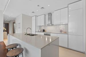 迪拜Brand New Spacious 2 Beds City Walk B9的白色的厨房配有白色的橱柜和凳子