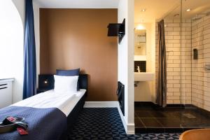 奥胡斯Milling Hotel Ritz Aarhus City的酒店客房配有一张床和淋浴