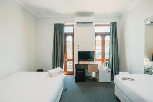 悉尼Newtown Cozy Stays的一间卧室配有两张床和一张带电脑的书桌