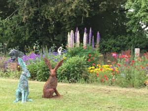 RaglanArt House B & B的两只兔子坐在鲜花盛开的花园中