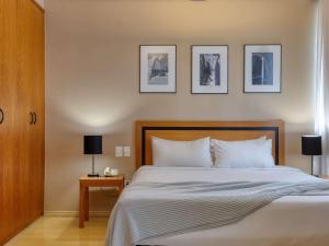 贝洛奥里藏特萨法斯美居BH酒店的卧室配有一张床,墙上有三幅照片