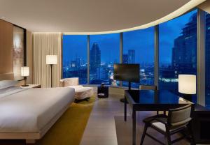 曼谷Park Hyatt Bangkok的一间卧室配有一张床、一张书桌和一个大窗户