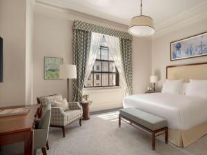 伦敦Raffles London at The OWO的配有一张床、一张书桌和一扇窗户的酒店客房
