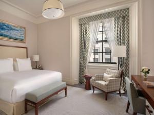 伦敦Raffles London at The OWO的一间卧室配有一张床、一张书桌和一个窗户。
