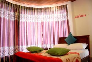 努沃勒埃利耶Nuwaraeliya Konical Villa的一间卧室配有一张带绿色枕头的床和一扇窗户