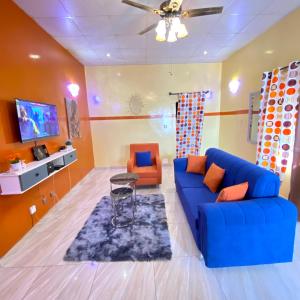 瓦加杜古Mini villa meublée pour vos séjours的客厅配有蓝色的沙发和橙色的椅子