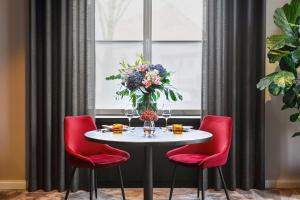 萨尔布吕肯ESPLANADE Saarbrücken的一张桌子,上面摆放着红色的椅子和花瓶