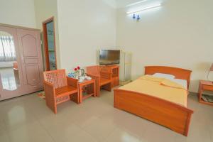 龙川市Nhà Hàng Khách Sạn Hòa Bình 2的一间卧室配有一张床、椅子和电视