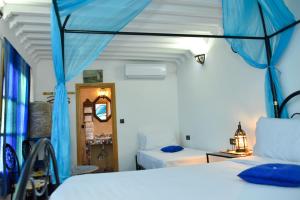非斯Riad Fes EL KAID的一间卧室配有两张蓝色窗帘的床