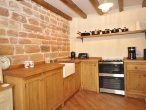 2 Bed in Newthorpe 47031的厨房配有木制橱柜和石墙