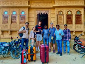 斋沙默尔Hotel Murad Haveli Jaisalmer的一群人站在大楼前,带着行李