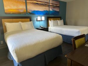 坦帕Days Inn & Suites by Wyndham Tampa - Ybor City的酒店客房设有两张床和一张桌子。