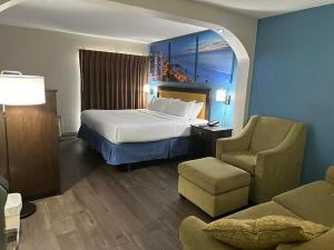 坦帕Days Inn & Suites by Wyndham Tampa - Ybor City的配有一张床和一把椅子的酒店客房