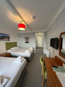 埃克斯茅斯The Imperial Hotel Exmouth的酒店客房设有两张床和电视。