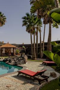圣巴尔托洛梅Finca Tomaren的一个带红色躺椅和棕榈树的度假游泳池
